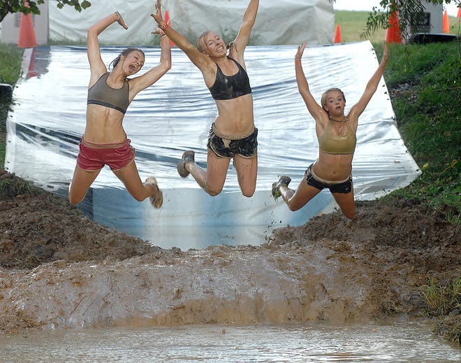 From left, Cassie French, 14, Ann Stone, 15, and Chynna Burton, 15, jump into a mud pit Saturday during The Epic Mud Run behind the Midway Travel Plaza