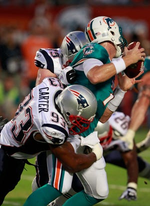Miami Dolphins quarterback Chad Henne (7) is sacked by New England Patriots defensive end Andre Carter (93) and Mike Wright (99) during the first half of an NFL football game Monday, Sept. 12, 2011, in Miami. (AP Photo/Wilfredo Lee)