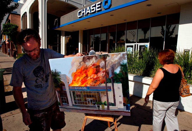 Artist Alex Schaefer stands in front of a Chase bank branch that was the inspiration for his oil painting depicting the structure on fire along Van Nuys Blvd. in Van Nuys, Calif., on Aug. 24. Schaefer has had the police visit him twice after he painted a plein air painting of the bank building on fire. Schaefer explained his paintings are intended to be a metaphor for economic havoc caused by banking practices. The painting is part of a series that will be in a show on the theme of "disaster capitalism" held at the Beacon Arts Building in February 2012. (The Associated Press/Los Angeles Times)
