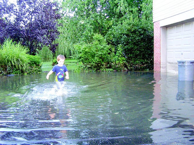Elijah Barrett, 2, splashed through water that filled the driveway at an Antrim Township residence. The water had already subsided by a foot, as indicated on the garage door. The tot and his parents, Dan and Carol Barrett, were helping friends assess the damage once the rain stopped and the sun reappeared Friday evening.