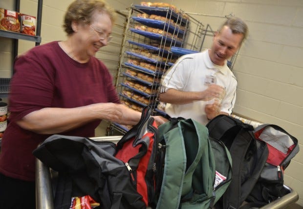 Ryan Wilson, an employee of Sodexo, the company that supplies
lunch food for Beaver Area High School, looks over backpacks that
will be filled with food and given to students with school employee
Mary Hinzy from Bridgewater.