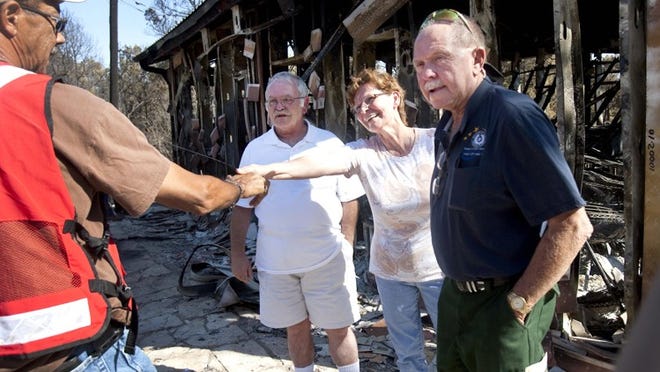Roselly Hendriks greets the Red Cross' Ronald Brooks on Sept. 10 in front of Roscar, the chocolates shop she owns with husband, Frans, center. The couple's home also was destroyed.