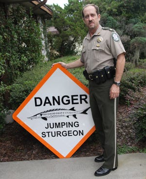 Florida Fish and Wildlife Conservation Commission Maj. Lee Beach, regional commander for the North Central Region, is shown with one of the sturgeon warning signs that have been posted on the Suwannee River. (Courtesy of the FWC)