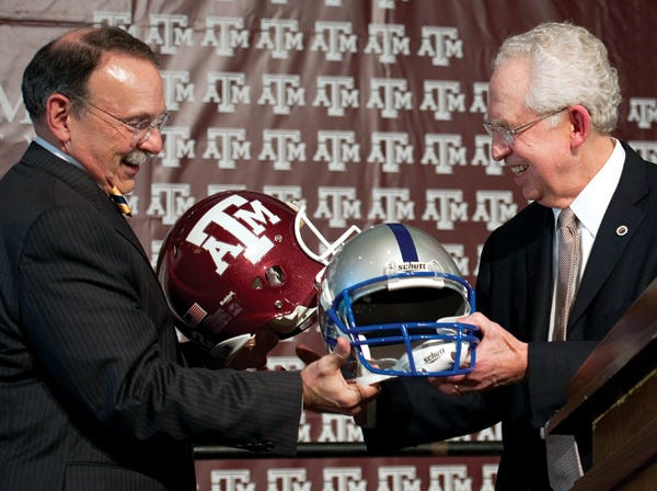 Texas A&M President R. Bowen Loftin, left, exchanges helmets with SEC Commissioner Mike Slive on Monday. 
(Dave Einsel | Associated Press)