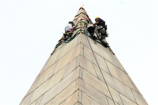 Engineers from Wiss, Janney, Elstner, Associates (WJE) test
their equipment at the top of the Washington Monument, on the
National Mall, in Washington, Tuesday, Sept. 27, 2011, preparing
for people to rappel down the sides to survey the extent of damage
sustained to the monument from the Aug. 23 earthquake. (AP
Photo/Jacquelyn Martin)