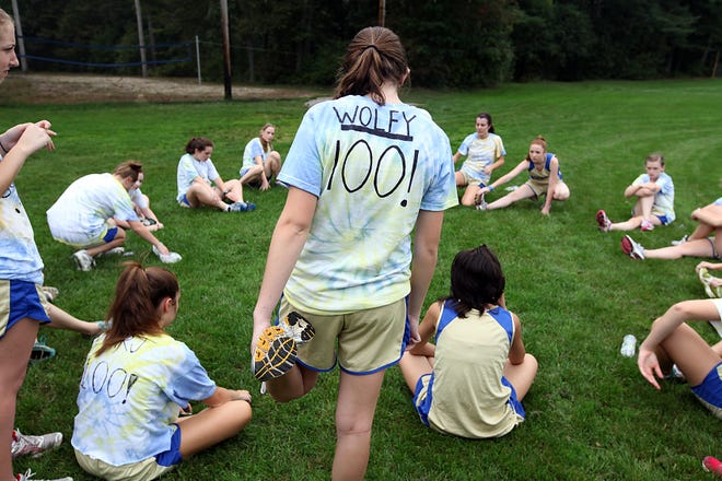 Norwell cross country runner Hannah Wolfson stretches out with the rest of the team while sporting a T-shirt predicting the Clippers' 100th league win before a meeting Tuesday, Sept. 27, 2011 against Abington.