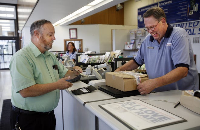 Bill Clary, left, mails a package Tuesday at the U.S. Postal Service’s Cook Street facility.