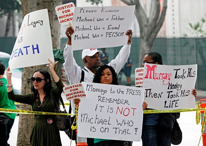 Michael Jackson fans hold signs outside court Wednesday during the involuntary manslaughter trial of Dr. Conrad Murray in Los Angeles. Murray has pleaded not guilty and faces four years in prison and the loss of his medical license if convicted of involuntary manslaughter in Michael Jackson's death. (The Associated Press)
