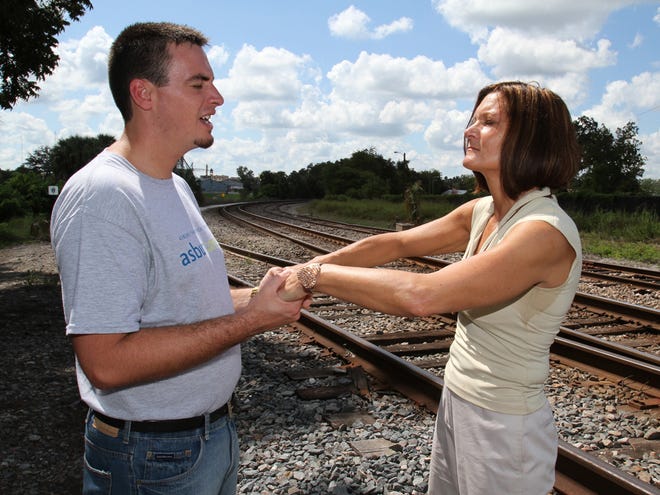 Diane Grochowski, right, prays with Michael Beck Wednesday along the railroad tracks at the place where her father committed suicide near Tuscawilla Park in Ocala.