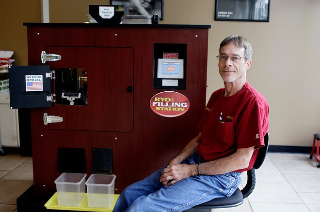 Bruce Hendren sits next to a cigarette-rolling machine at Roll On.