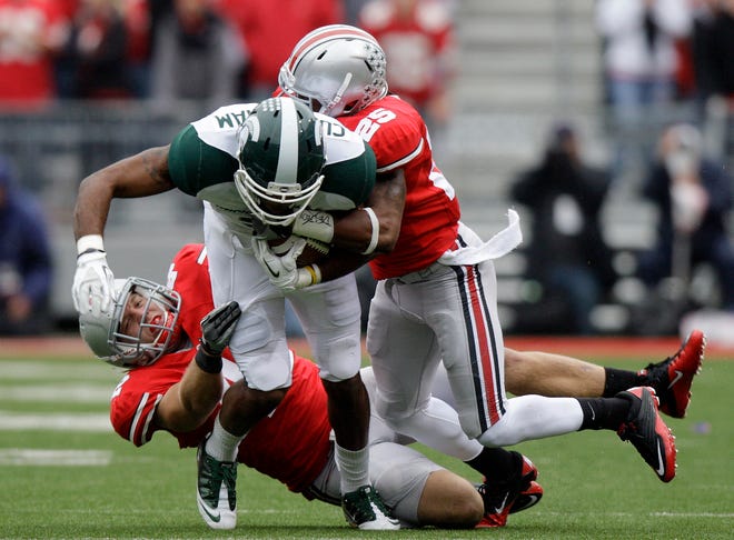 Michigan State's B.J. Cunningham (center) catches the ball for a first down as Ohio State's Andrew Sweat (left) and Bradley Roby tackle him Saturday in Columbus, Ohio.