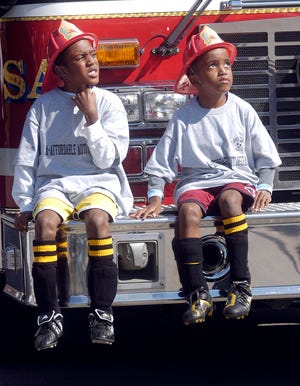 Christian Bonny, 7, and his brother Daniel, 5, both of Brockton, sit on the front bumper of a fire truck as they watch a firefighter climb Ladder 4 during the Brockton Fire Department’s open house at the West Street fire station on Saturday.