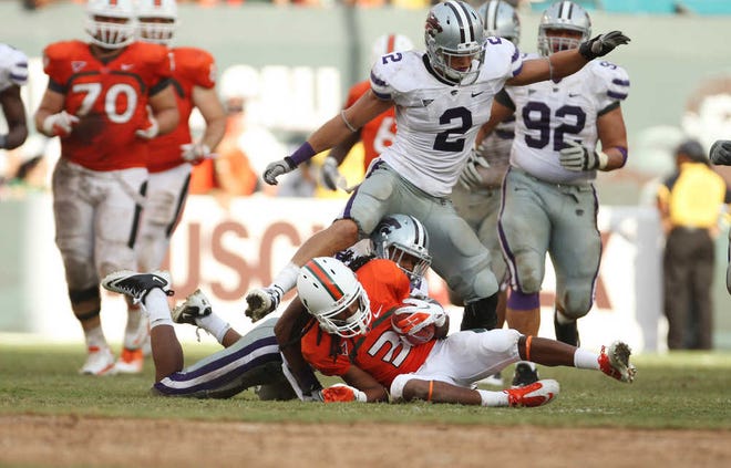 Kansas State's Tysyn Hartman (2) steps over a downed Miami's Travis Benjamin (3) during the second half of the NCAA college football game in Miami, Saturday, Sept. 24, 2011. Kansas State defeated Miami 28-24. (AP Photo/J Pat Carter)