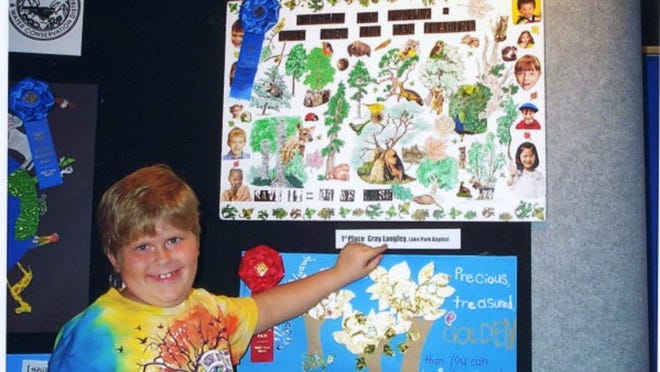 Lake Park Baptist School student Gray Langley shows off his award-winning poster at the South Florida Fair in January. Gray, now 7, created the poster as part of the Palm Beach Soil & Conservation District’s 2011 Conservation Poster Contest.