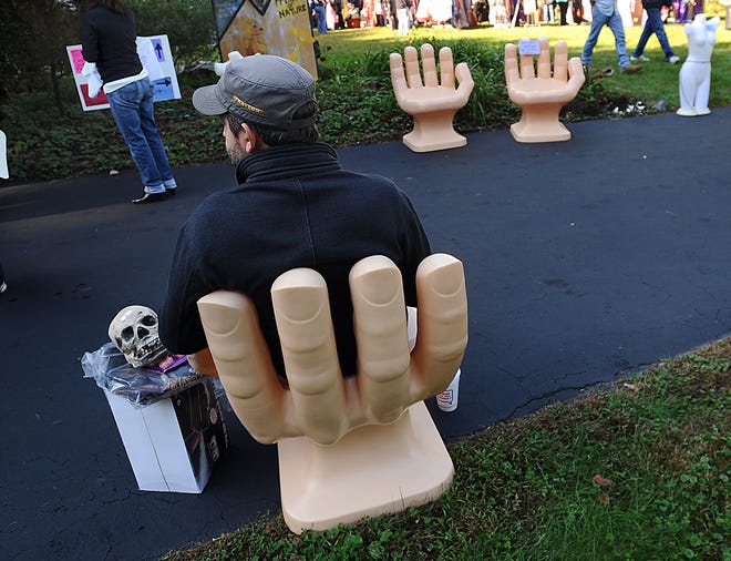 A customer rests on a hand chair after picking out a skull during an estate sale at the Sudbury home of former Spooky World owner David Bertolino.