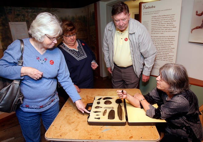 Judy Fichtenbaum, an educational assistant at the Concord Museum talks about a display of ancient stone tools found in the Concord area with Janice Caldwell of Missouri, left, and Winona and Bill Caldwell of Tennessee during an event Saturday at the museum.