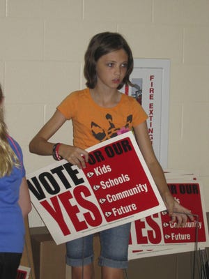 Jessie Thompson, 13, a seventh-grader in London City Schools, helps assemble yard signs urging passage of the district's five-year, 8.5-mill levy.