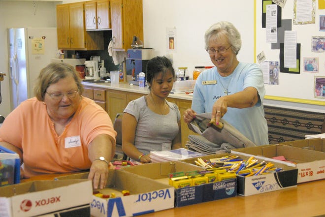 Pat Wright, right, helps Becki Escondo, middle, and Sandy Bittner, prepare a school kit at the Midwest Mission Distribution Center in Chatham. Wright is the executive director at MMDC.
