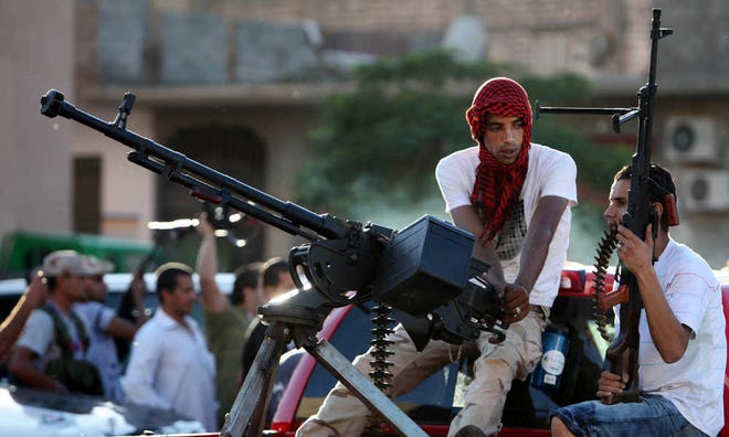Revolutionary fighters sit on a truck mounted with a machine gun in the Abu Salim neighborhood of Tripoli, Libya, Friday, Oct. 14, 2011. A gunbattle erupted Friday between hundreds of revolutionary forces and Moammar Gadhafi supporters in the capital for the first time in more than two months after loyalists tried to raise the green flag that symbolizes the ousted leader's regime. The fighting began when dozens of loyalists carrying the green flag appeared on the streets of Tripoli's Abu Salim neighborhood, which houses the notorious prison of the same name.(AP Photo/Abdel Magid al-Fergany)