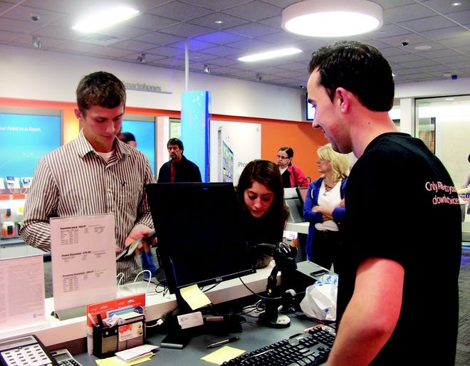 AT&T store employee Brandon Doud helps Chris Lawrence and Leah McDermott with a new iPhone 4S purchase at Eastview Mall.
