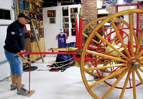 Photo by Jessica L. Mickley/New Jersey Herald 
 
Franklin Fire Chief Fred Babock Jr. lifts the fire department’s antique hose carrier back into place. The Franklin Fire Department celebrated its 100th anniversary this year.