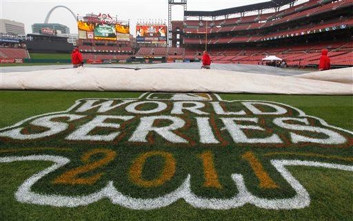 Workers remove a tarp from the infield at Busch Stadium on Wednesday, Oct. 26, 2011, in St. Louis, after officials announced that Game 6 of baseball's World Series is postponed due to rain.
