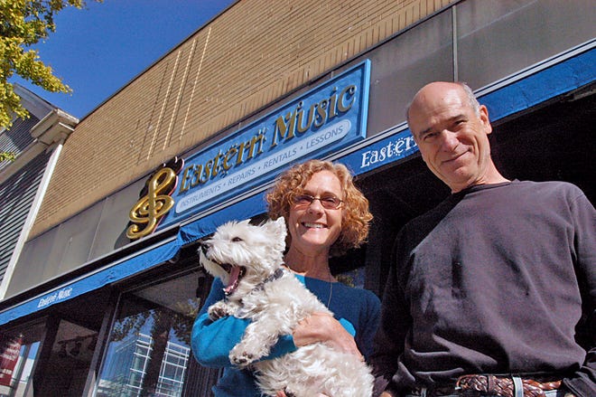 Patia Campbell, owner of Eastern Music, is moving her business to Main Street. Campbell is seen here holding dog Zoe and standing next to instrument repairman Ray Longo.