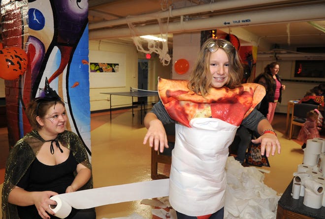From left, Bridgewater State University student Michelle Paradiso, 19, Rutland, wraps Juliana Nakouzi, 9, Bridgewater, with toilet paper. Trick-or-treating at Bridgewater State University's Woodward Hall, on Monday, October 31, 2011. As students distribute candy to from their dorm rooms to the public. There is also games and food in the basement of Woodward Hall.