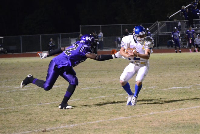 East Ascension quarterback Adam Miller maneuvers away from a Woodlawn defender Friday night.