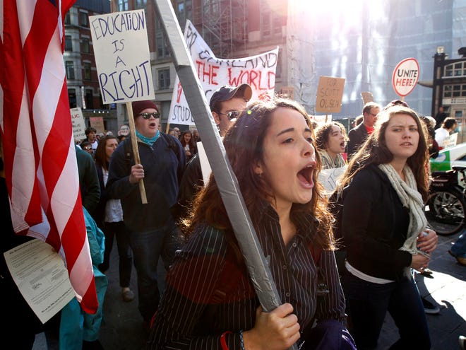 Protester Alexis Marvel, of Boston, front, holds an American flag and shouts slogans while joining with members of the Occupy Boston movement, students from area colleges and union workers as they march through downtown Boston on Wednesday. (AP Photo/Steven Senne)