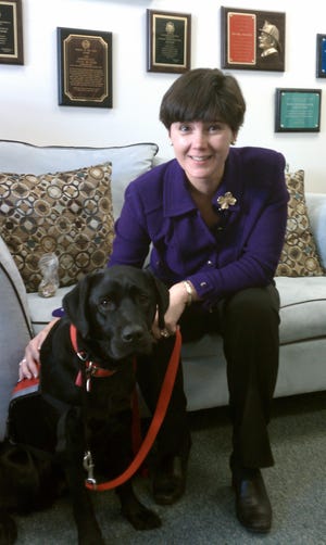 State Rep. Carolyn Dykema, D-Holliston, spends time with a dog trained to help people with disabilities.