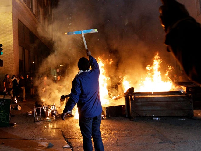 An Occupy Oakland protester holds up a sign in front of a bonfire in Oakland, Calif., Thursday, Nov. 3, 2011. (AP Photo)