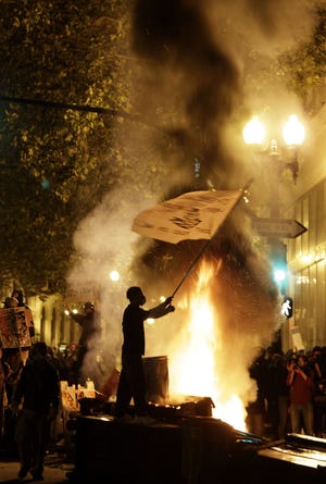 An Occupy Oakland protester waves a flag next to a bonfire in Oakland, Calif., Thursday, Nov. 3, 2011. (AP Photo/Jeff Chiu)