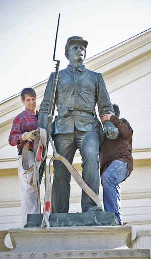Workers adjust the position of Randolph’s 100-year-old Civil War statue after it was lowered back into place.