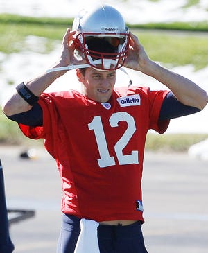 Patriots quarterback Tom Brady puts on his helmet during practice on Wednesday in Foxboro.