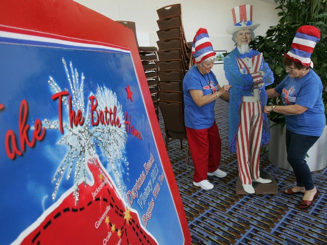 In this Thursday, Nov. 3, 2011 photo, Aileen Milton and Lynda DeHart slide a life-sized cutout of Uncle Sam in place while setting up for the Tea Party Convention in Daytona Beach, Fla., at the Ocean Center. (The Associated Press)