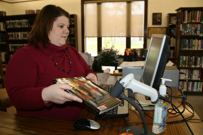 Warren Township Public Library director Jenny Carter checks in a book using the automotive computer system. Each book needed to have a barcode. Carter and her library team spent many hours upgrading the system.
