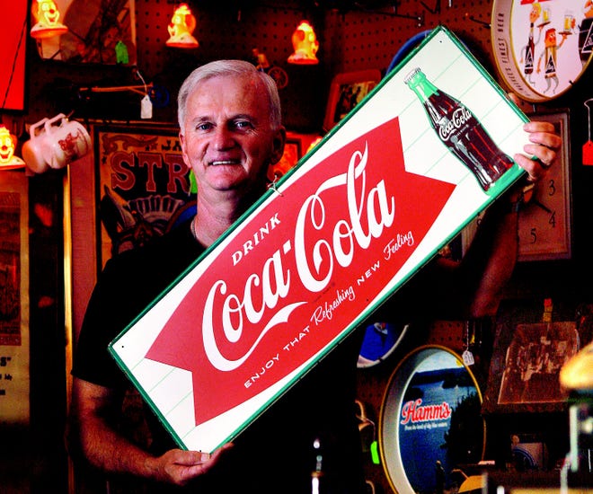 Dan Fulk, owner of 49er Antiques & Collectibles in Lincoln, shows off a vintage metal Coca-Cola sign from 1963 with an asking price of $175. David Spencer/The State Journal-Register