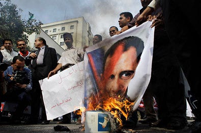 Protesters with a sign reading “Death to You” burned a picture of President Bashar al-Assad of Syria outside the Arab League offices in Cairo on Saturday.