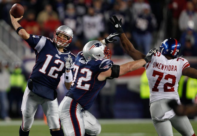 Patriots' Tom Brady, left, passes as Matt Light holds off Giants' Osi Umenyiora during last Sunday's game in Foxboro.