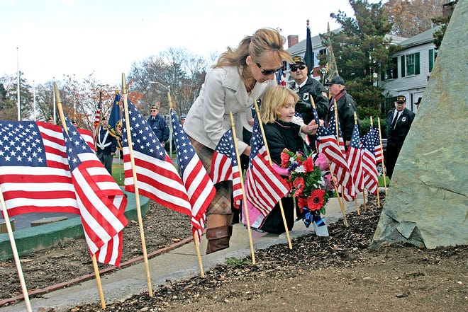 State Rep. Shaunna O'Connell, helps her daughter Riley,6, place a flag at the Vietnam Vets Memorial on Church Green.