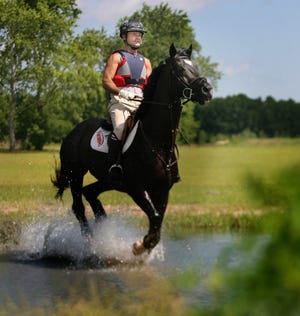 In this May 15 file photo, Darren Chiacchia and his black stallion, Zauberruf, through a water obstacle during a cross country schooling day at the Florida Horse Park.
