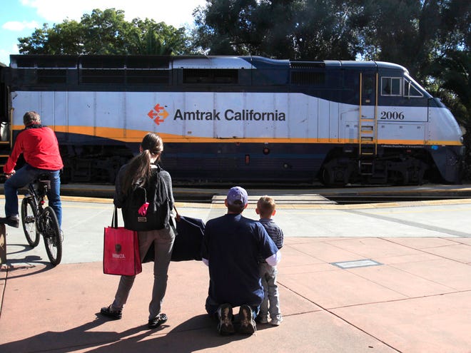 In this photo taken Friday, Nov. 4, 2011, David Roberts, kneeling center, his son Jeremey three-and-a-half, and niece Holly Bodsen, right, watch as Amtrak's Capitol Corridor passenger train departs Davis, Calif. (AP Photo)