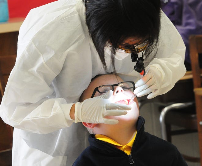 Mital Spatz, PharmD, DDS, checks Center School second-grader Devin Brown's teeth Thursday at the school. Spatz and Jason Grinter, DDS, MPH, offer complete dental service at the Stephenson County Health Department Dental Clinic.