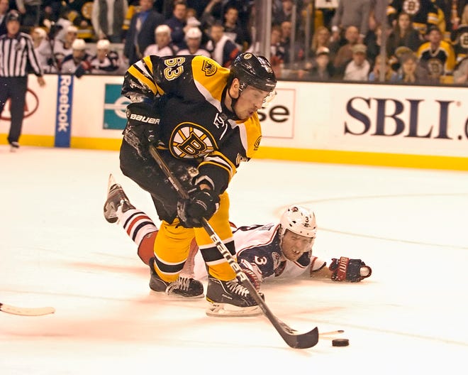 Bruins' Brad Marchand shoots a back-hander shot as Columbus' Marc Methot attempts to block it.
