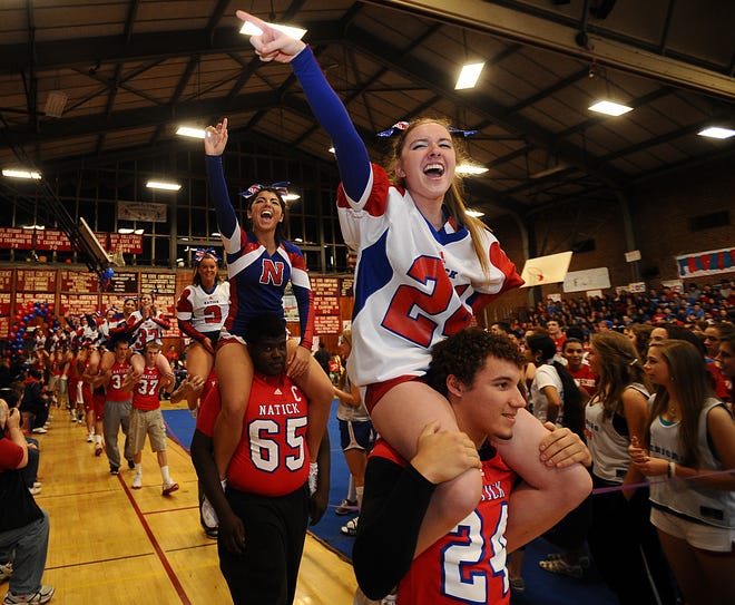 Natick High School football player Corey Fisher and cheerleader Courtney Caccavelli, right, followed by football player Evans Dorime and cheerleader Annie MacLellan, enter the gym for the school's annual pre-Thanksgiving pep rally Wednesday.
