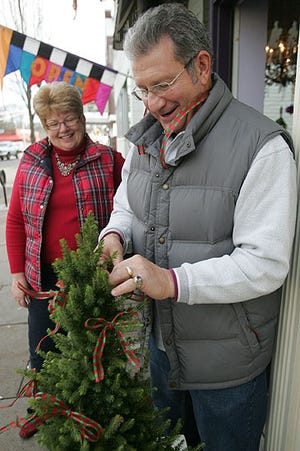 Photos by Amy Herzog/New Jersey Herald Bonnie Bitondo left, supervises her husband, Rick Bitondo, Saturday as he decorates the Christmas trees outside her shop, Maxwell and Molly’s Closet Pet Boutique. on Spring Street in Newton.