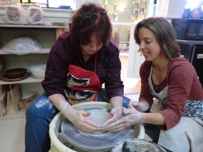 Dot Burnworth, right, helps Nanci Westlake, of Mansfield Center, make a pot Saturday at
Burnworth’s Sawmill Pottery studio in Putnam. Burnworth offered a pottery class during Small Business Saturday.