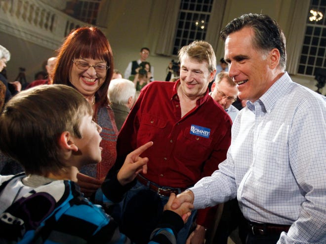 Former Massachusetts Gov. Mitt Romney, right, greets a young supporter during a town hall event in Peterborough, N.H. on Nov. 19. A poll released last week showed him with 42 percent support among likely Republican primary voters in New Hampshire. (The Associated Press)