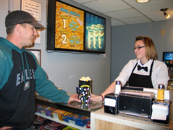Popcorn and a movie: Jim Goebel, left, purchases popcorn from concessionist Michaela Grant. Goebel, of Ozark, Ala., is a former Chillicothean.